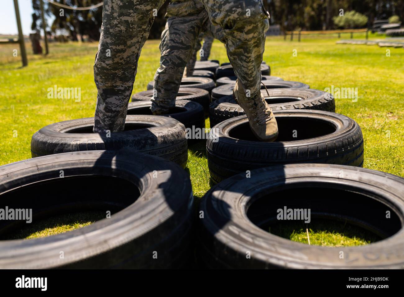 Low section of group of diverse soldiers walking on tires during obstacle course at boot camp Stock Photo