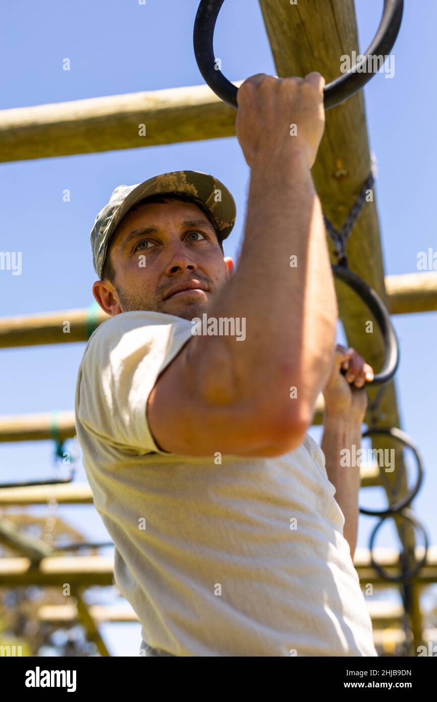 Close up of caucasian male soldier climbing monkey bars during obstacle course at boot camp Stock Photo