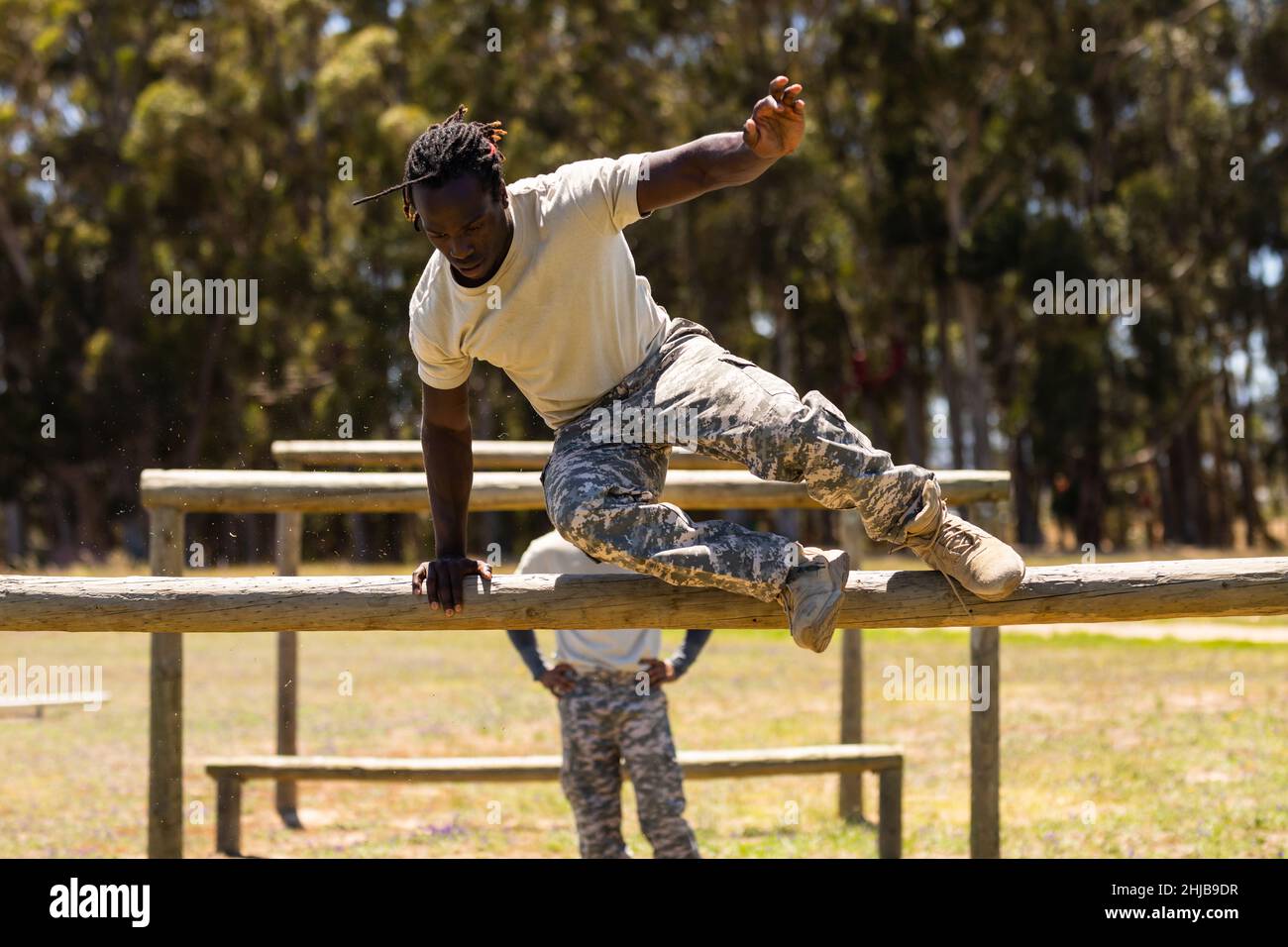 African american male soldier jumping over wooden hurdles during obstacle course at boot camp Stock Photo