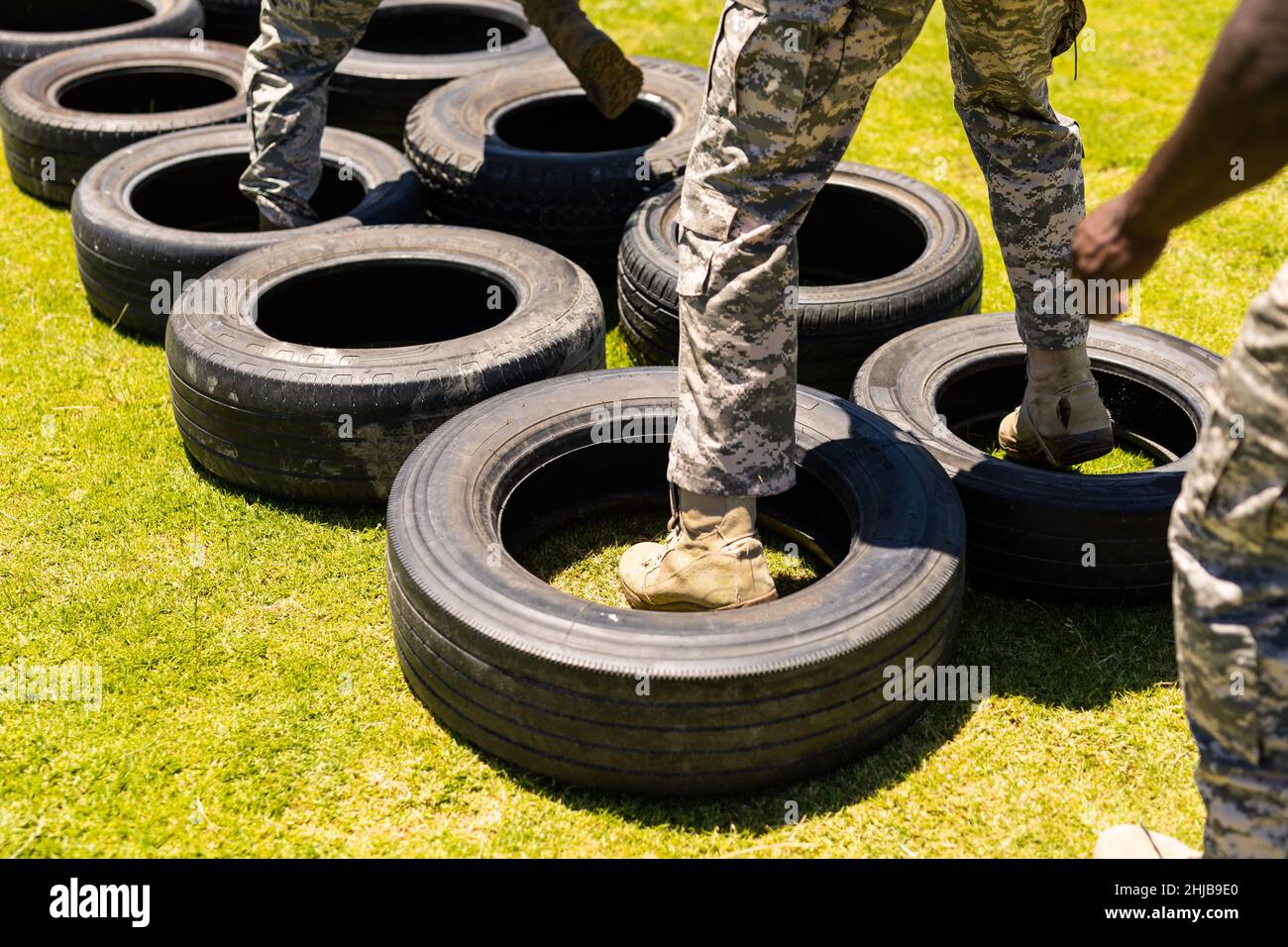 Low section of diverse male and female soldiers walking on tires during obstacle course at boot camp Stock Photo