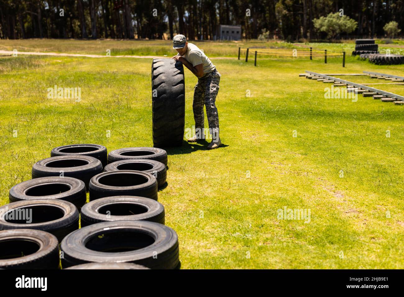 Male soldier rolling a tire during obstacle course at boot camp Stock Photo