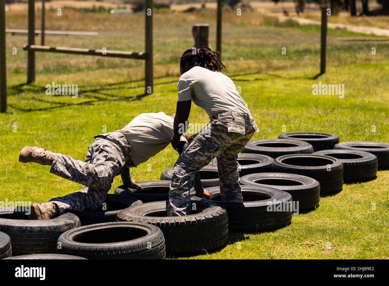African american male soldier helping other male soldier during tire obstacle course at boot camp Stock Photo