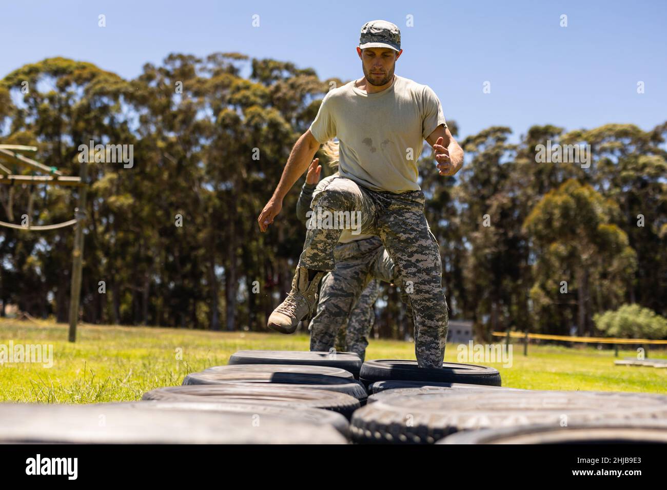 Caucasian male soldier walking on tires during obstacle course at boot camp Stock Photo