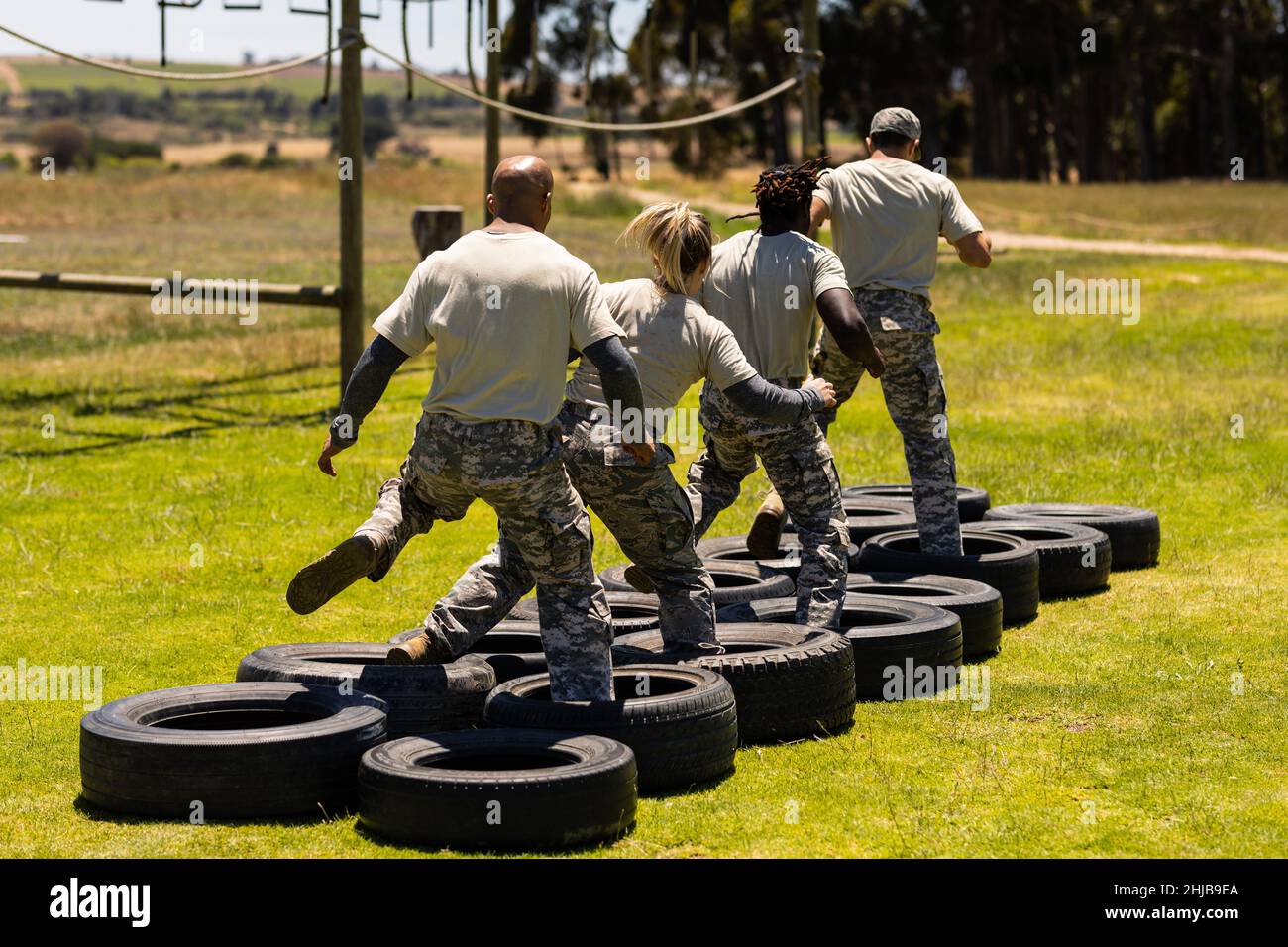 Rear view of group of diverse soldiers walking on tires during obstacle course at boot camp Stock Photo