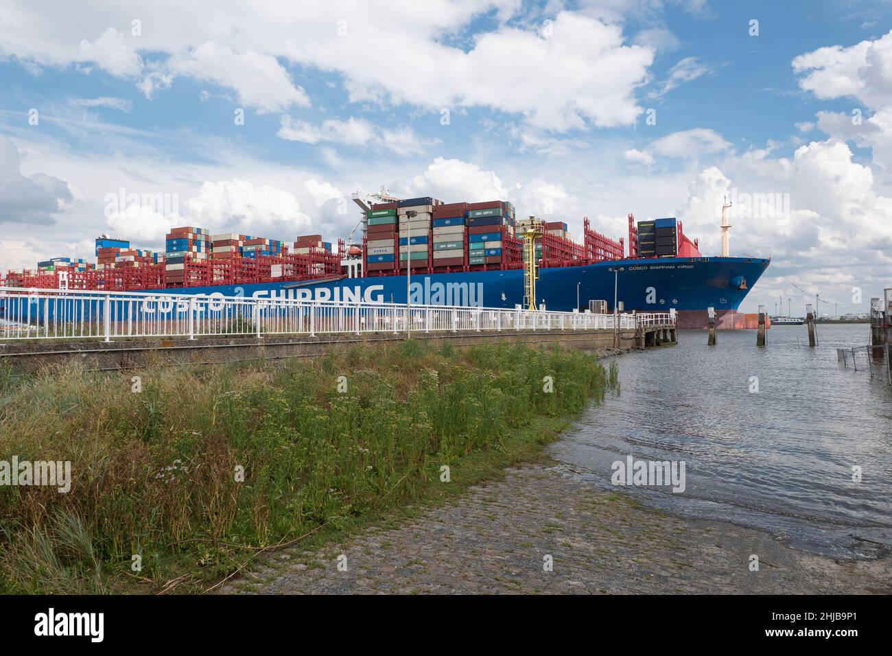 Doel, Belgium, August 17, 2020, The container ship Cosco Shipping from Hong Kong, sails very close to the pier of the polder village of Doel in Belgiu Stock Photo
