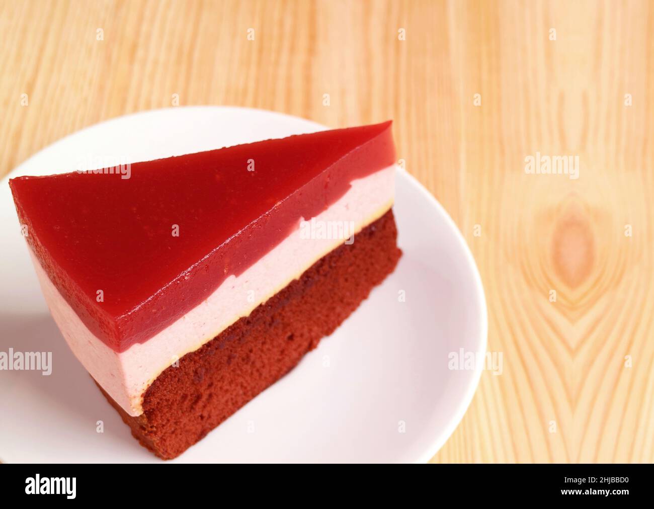 A Slice of Raspberry Mousse with Chocolate Layer Cake on Wooden Backdrop Stock Photo