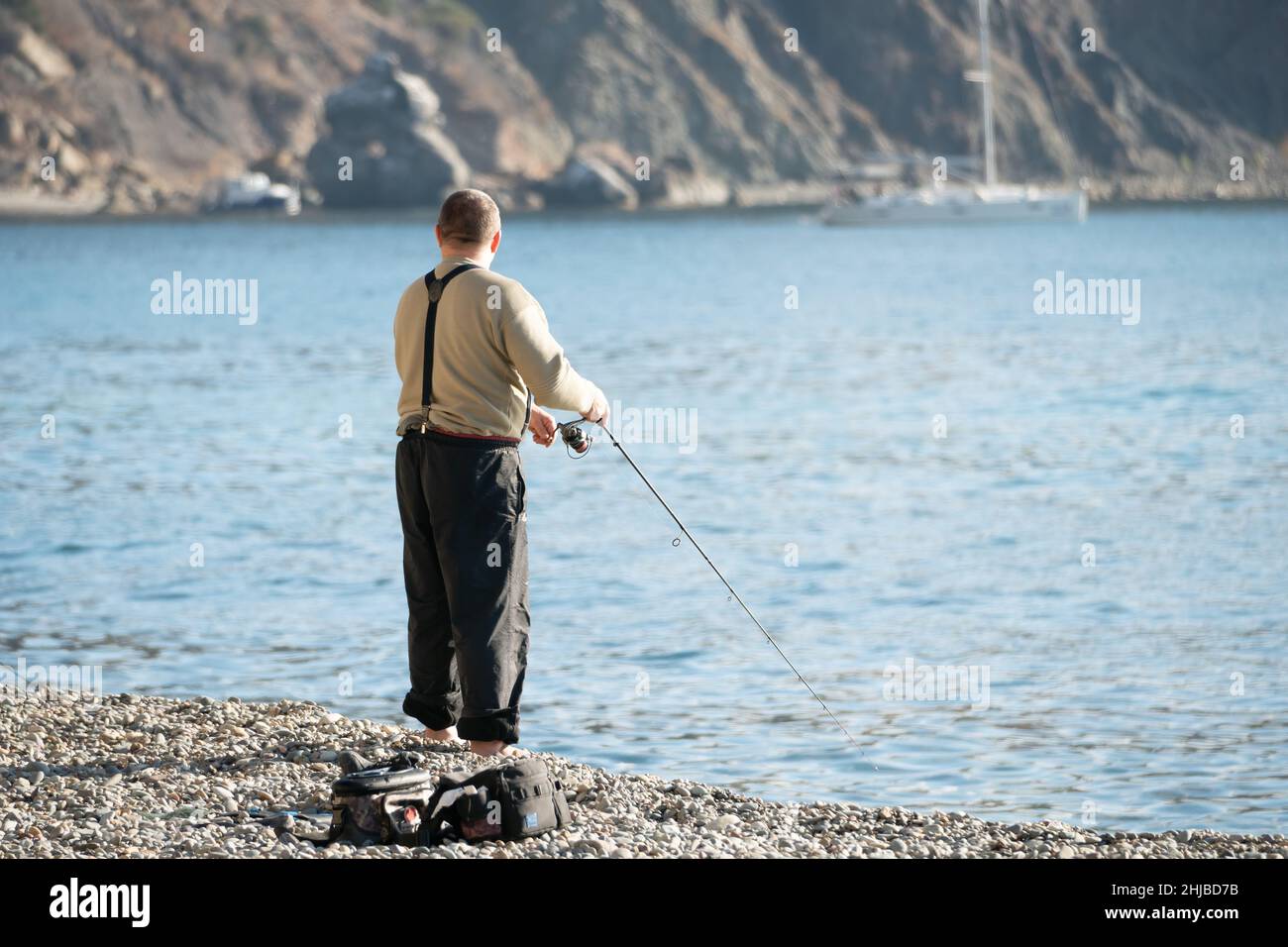 A sea angler reeling in with a fixed spool reel that has been loaded with  braided fishing line while shore fishing. Braided fishing lines have  virtual Stock Photo - Alamy