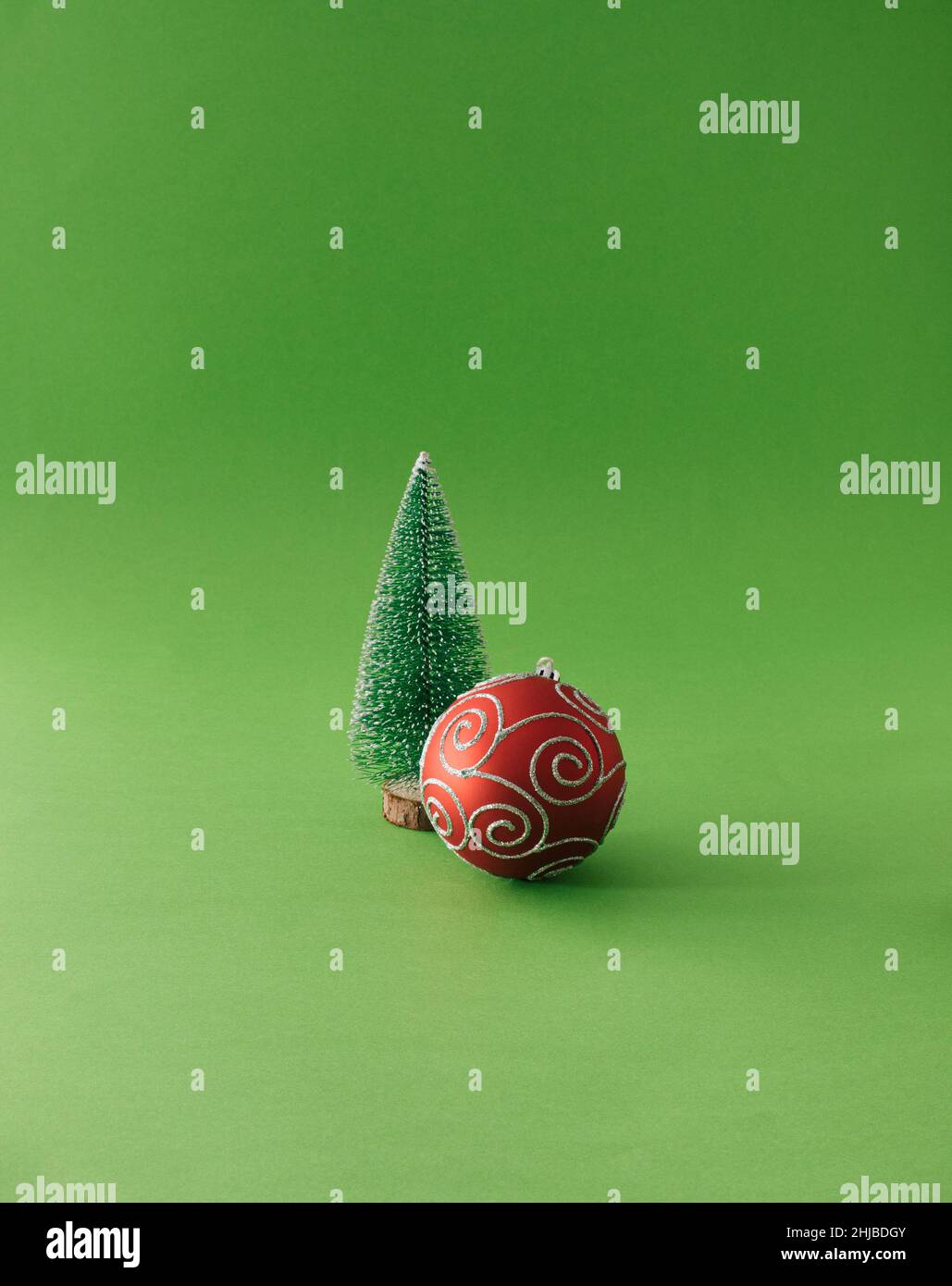Christmas tree with red bobbles on a green background. Minimal New Year's concept. Stock Photo