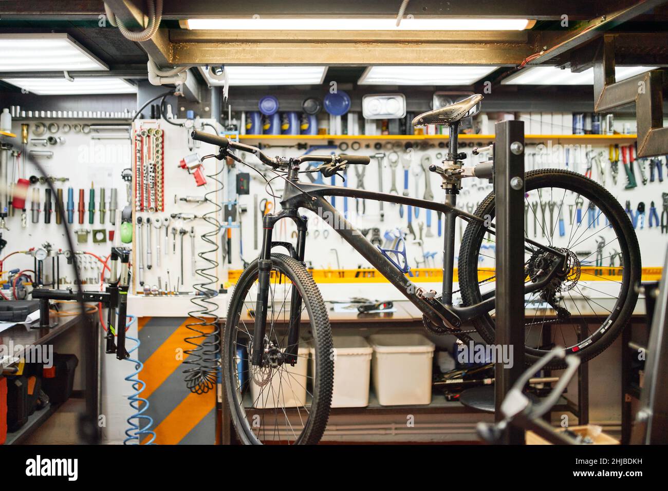 Broken bike placed on rack against workbench with tools in professional ...