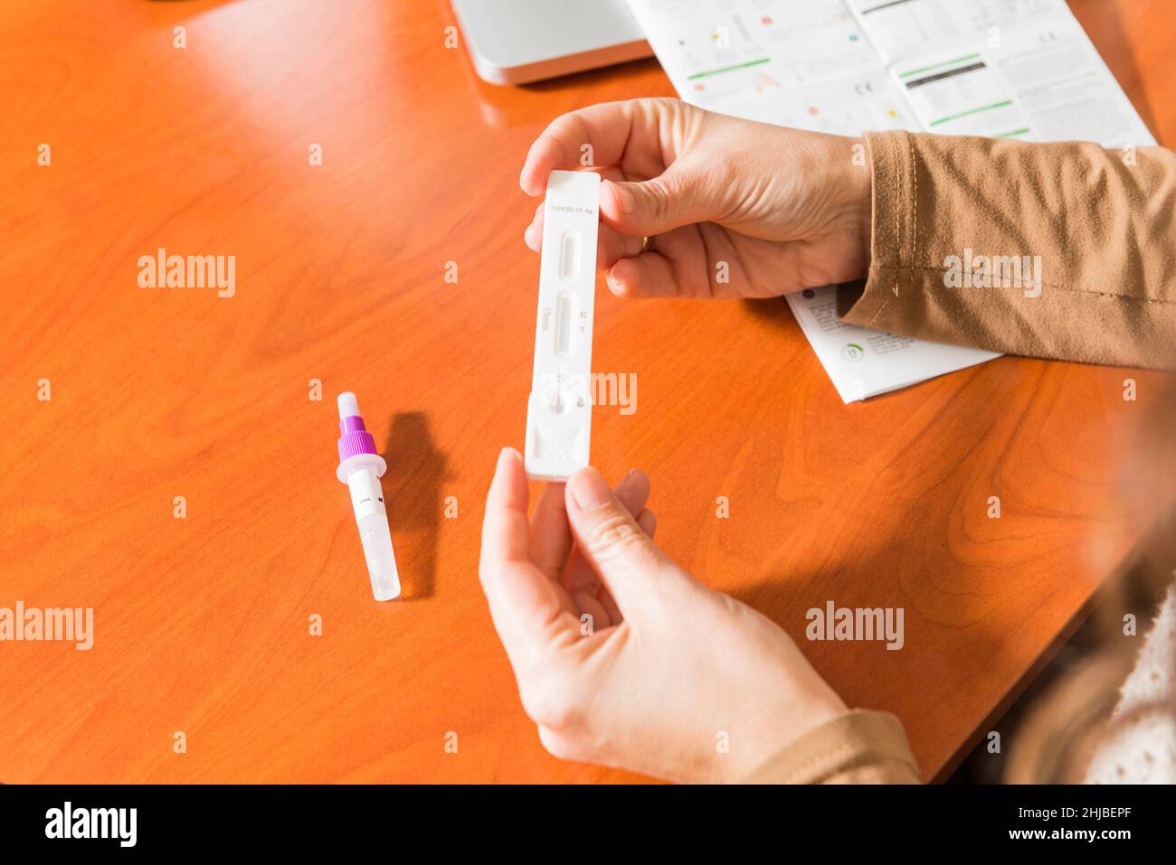 Detail of a woman's hands holding an antigen test cassette and reading