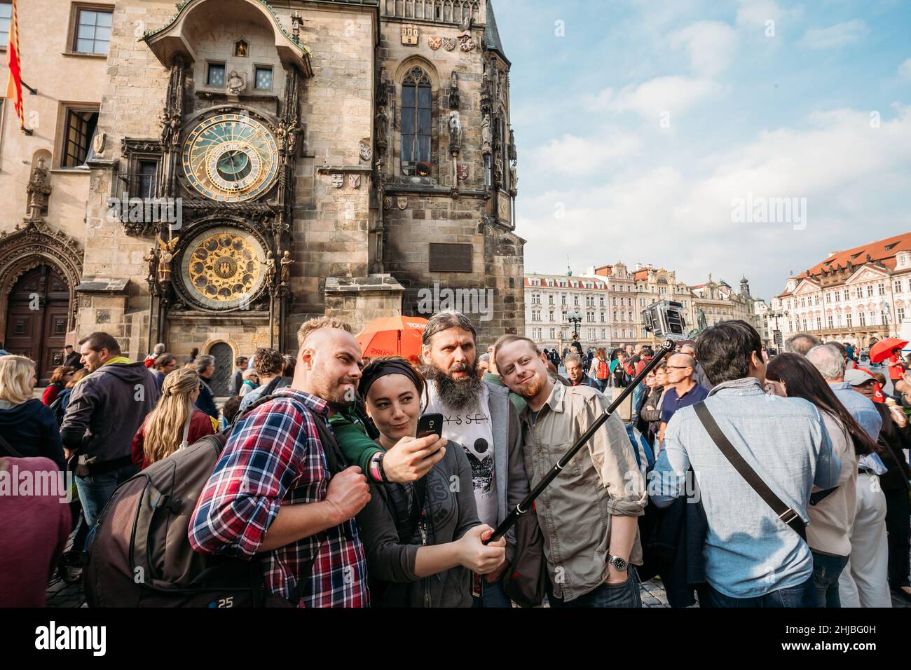 Group of tourists taking pictures against background of sights - town hall with astronomical clock - orloj in Prague, Czech Republic Stock Photo