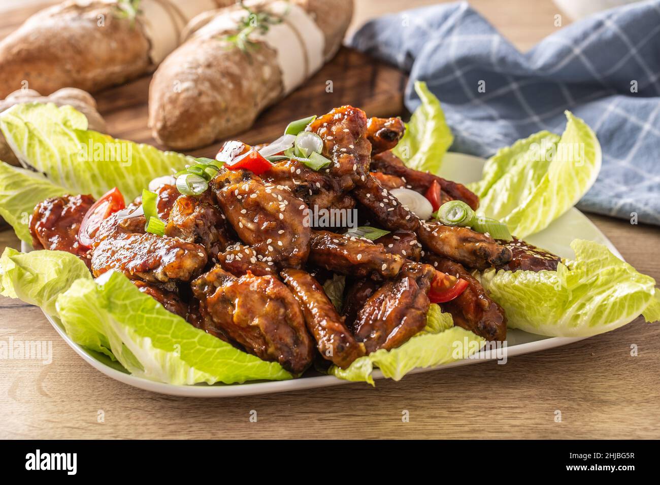 Asian chicken wings in a sticky spicy marinade sprinkled with sesame and served on salad leaves. Stock Photo