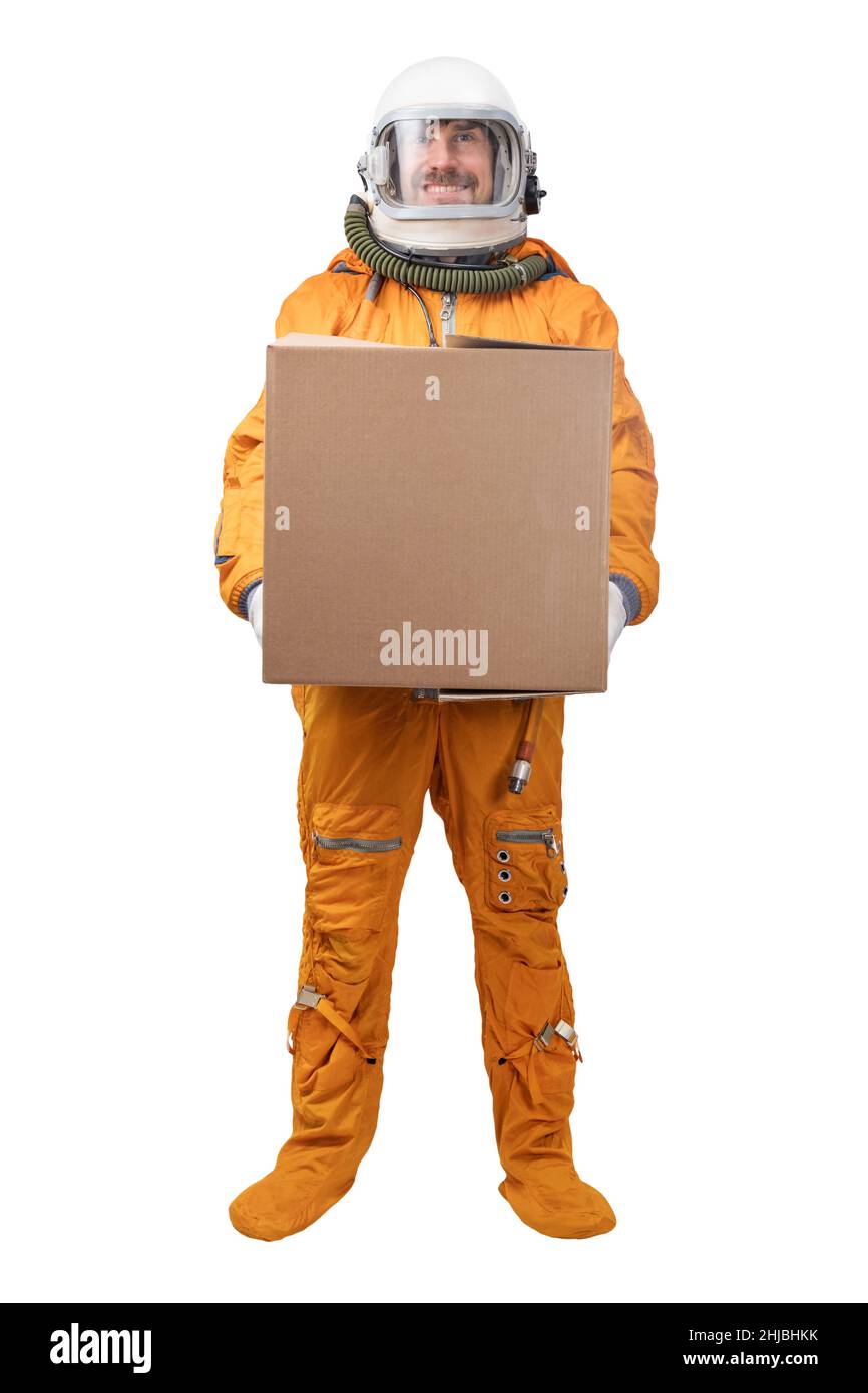 Astronaut wearing orange space suit and space helmet holding in hand blank square cardboard box isolated on white background Stock Photo