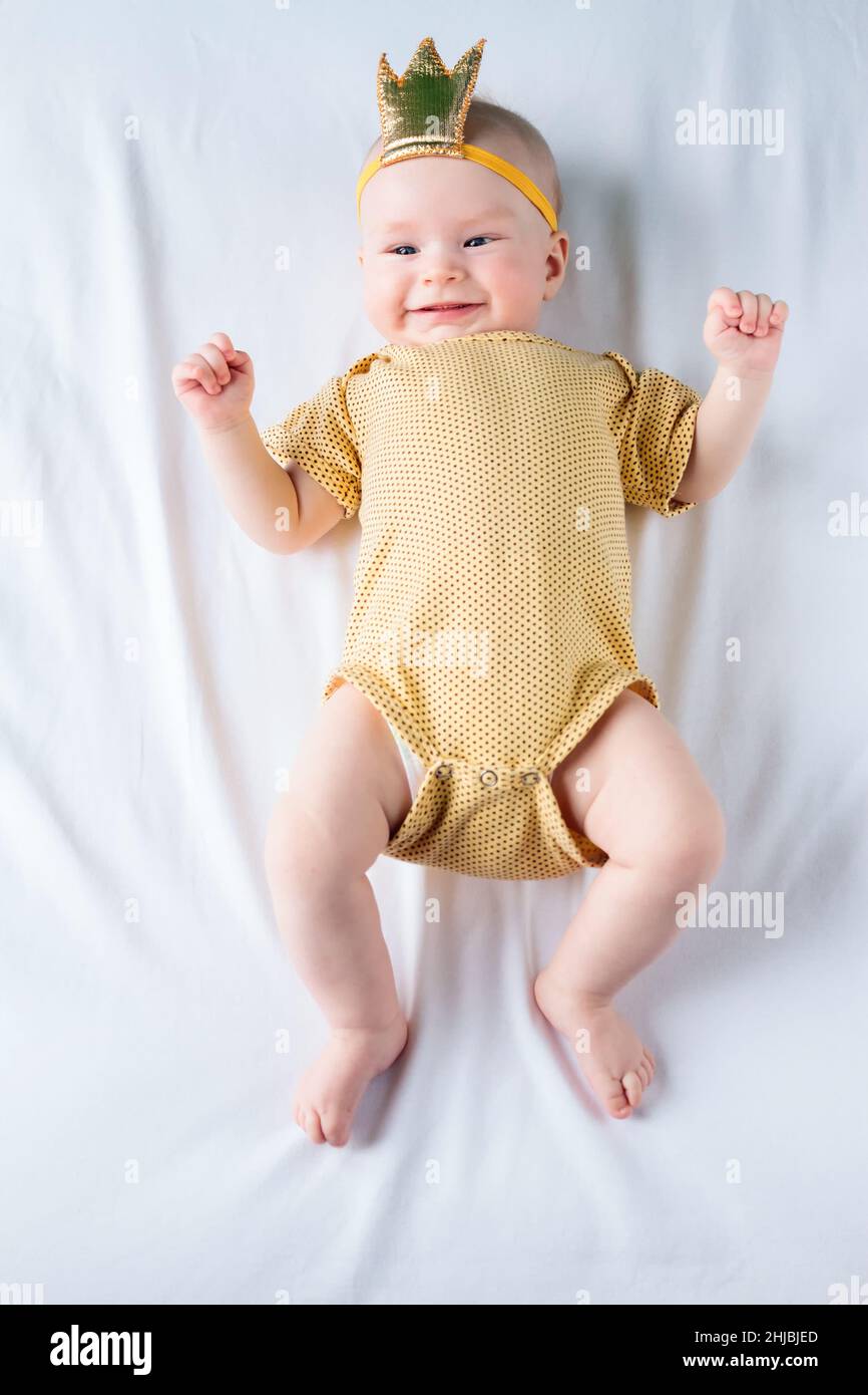 Sweet 4-months-old baby girl lying on the white sheet in bed at home Stock Photo