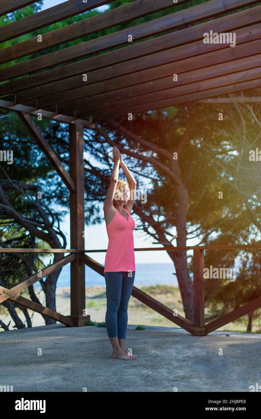 Young serious woman wearing sportswear woman doing yoga in a wooden pergola outdoors Stock Photo
