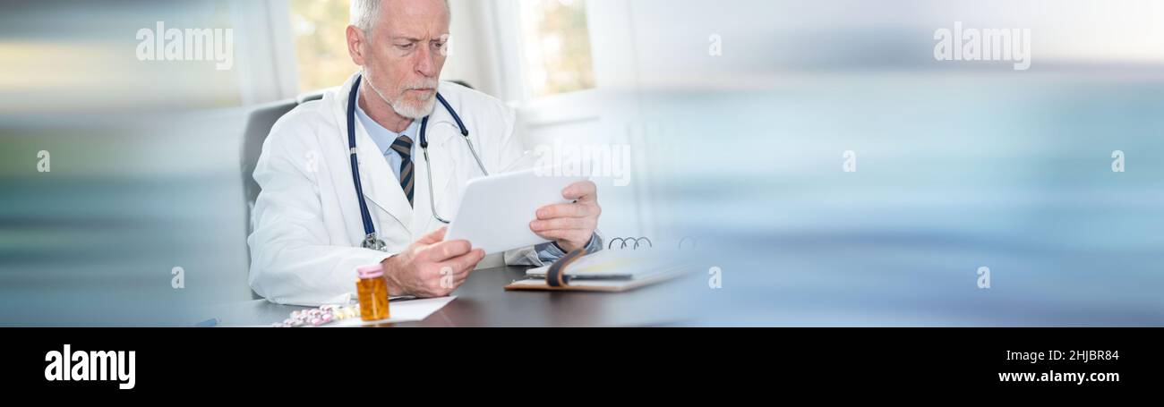 Senior doctor using tablet in office on blurred background Stock Photo