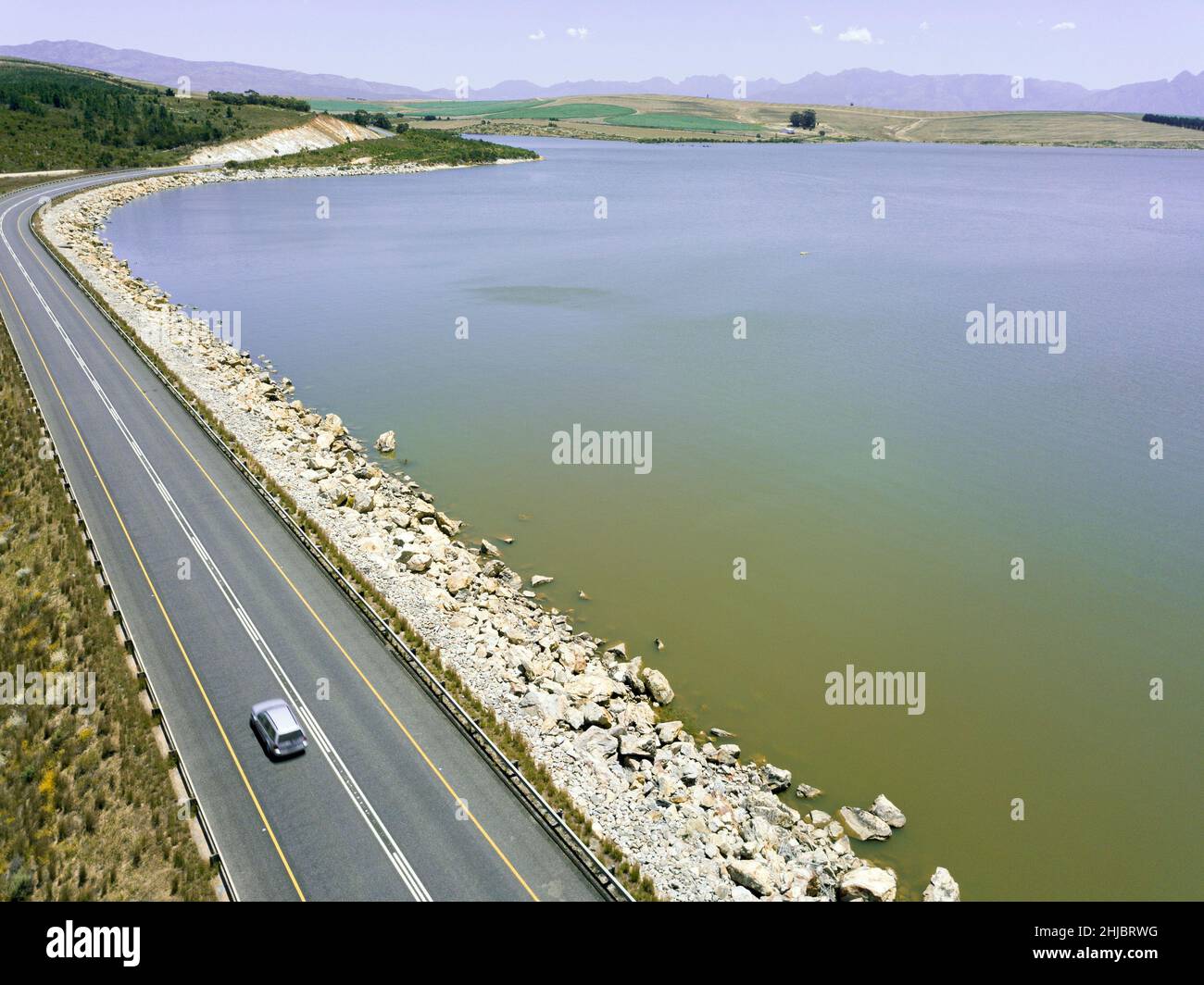 Aerial of car driving across a dam wall Stock Photo
