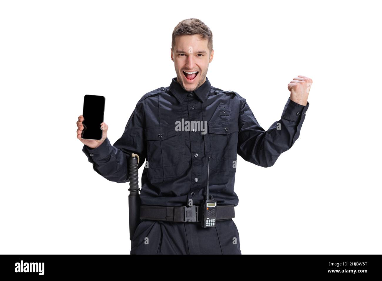 Portrait of young man, policeman officer wearing black uniform using phone isolated on white background. Concept of job, caree, law and order. Stock Photo