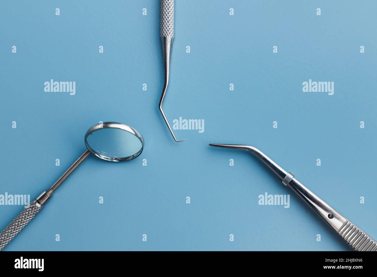 Professional dental hand tools set on blue background, mirror, hook and