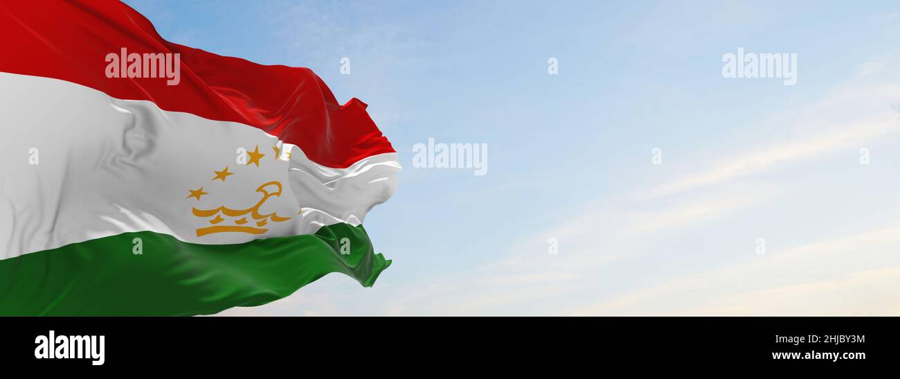 official flag of Tajikistan at cloudy sky background on sunset, panoramic view. patriot and travel concept. copy space for wide banner. 3d illustratio Stock Photo