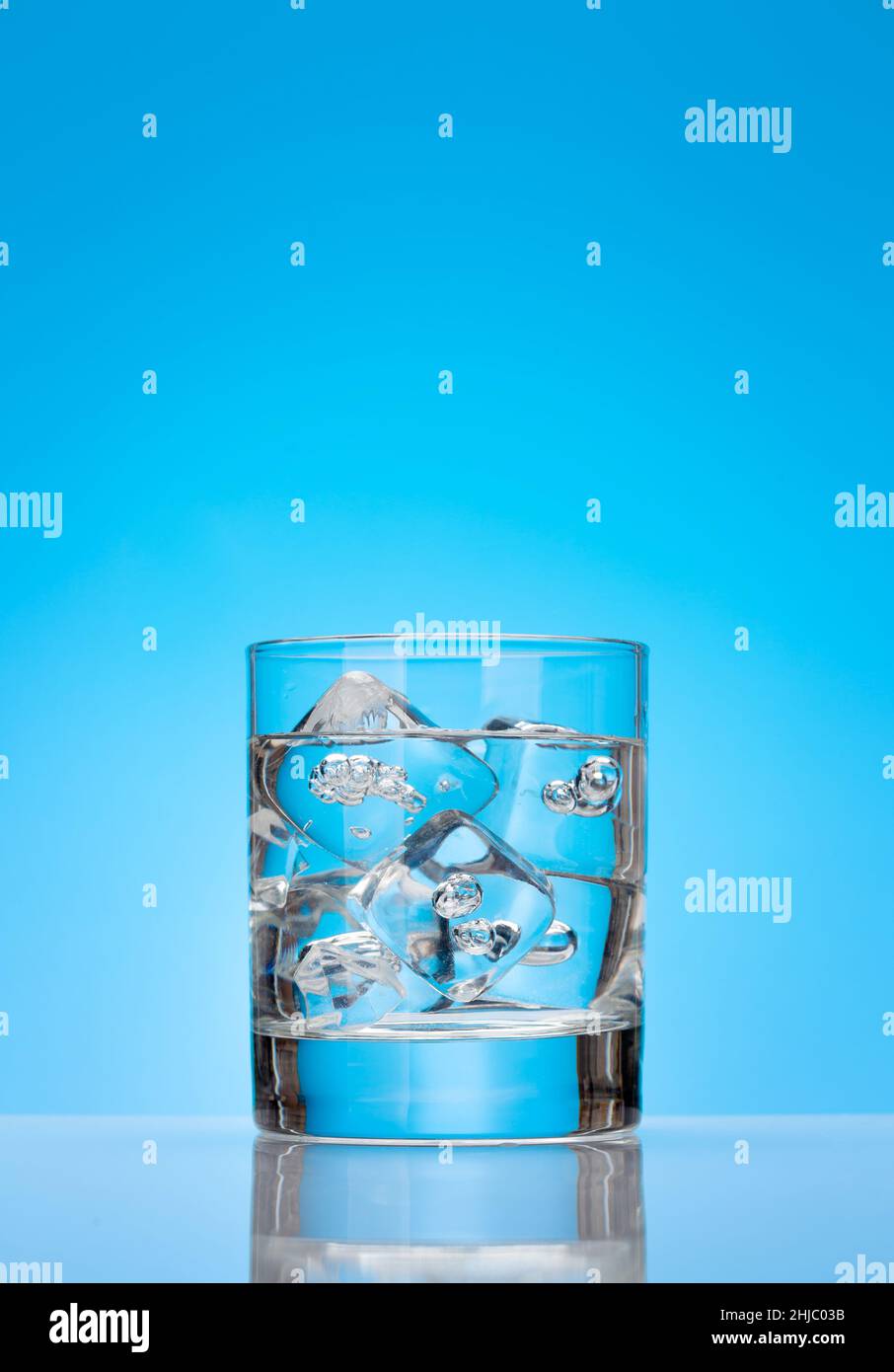 Glass with water and ice cubes over blue background Stock Photo - Alamy