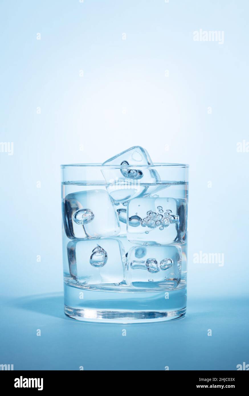 Glass with water and ice cubes over blue background Stock Photo - Alamy