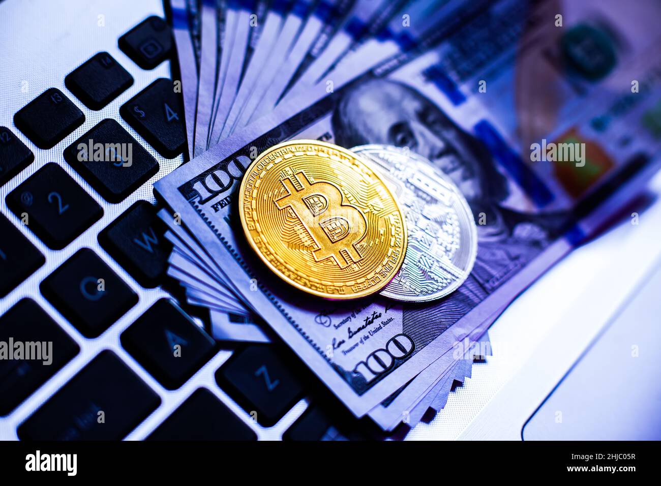 Bitcoin on a laptop keyboard and hundred-dollar bills in neon light. Payment  in cryptocurrency in the metaverse. Selective focus Stock Photo - Alamy