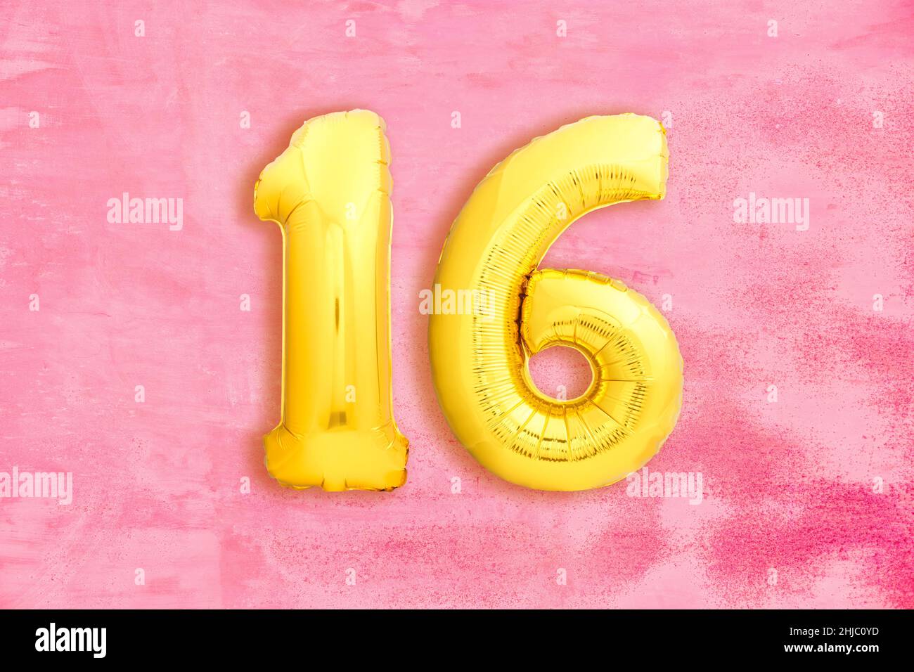 Number 16 sixteen made of golden inflatable balloons on pink grungy background Stock Photo