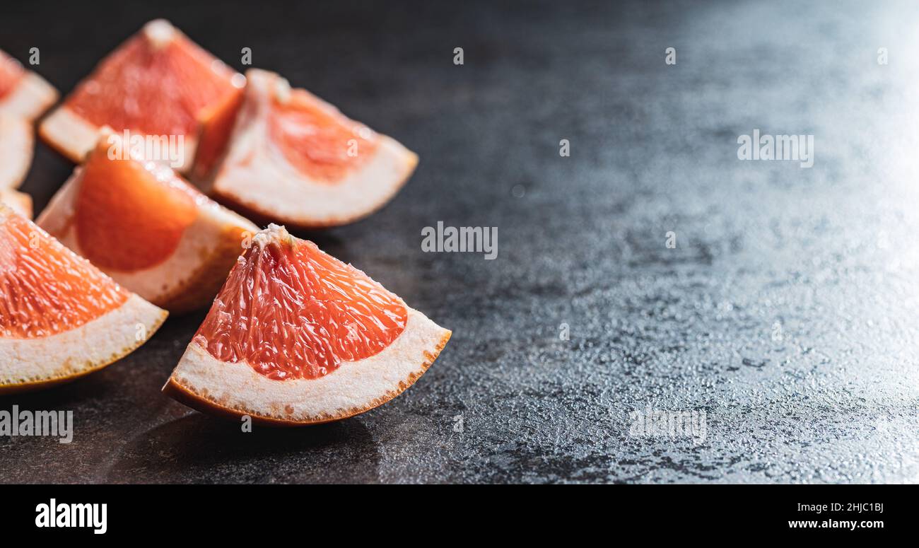 Sliced citrus fruit. Chopped fresh grapefruit on a black table. Stock Photo