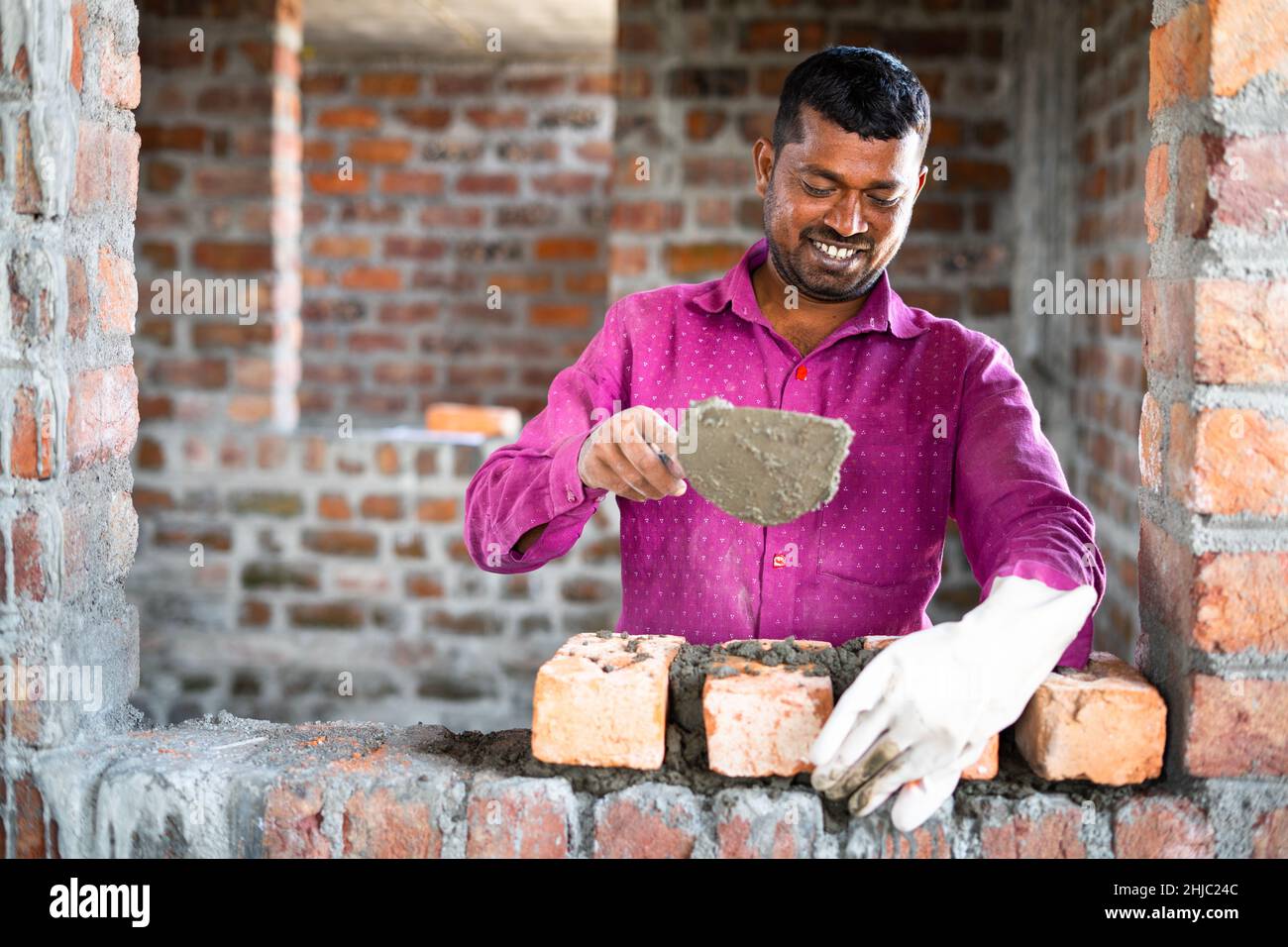 Happy smiling construction worker constructing or building wall by