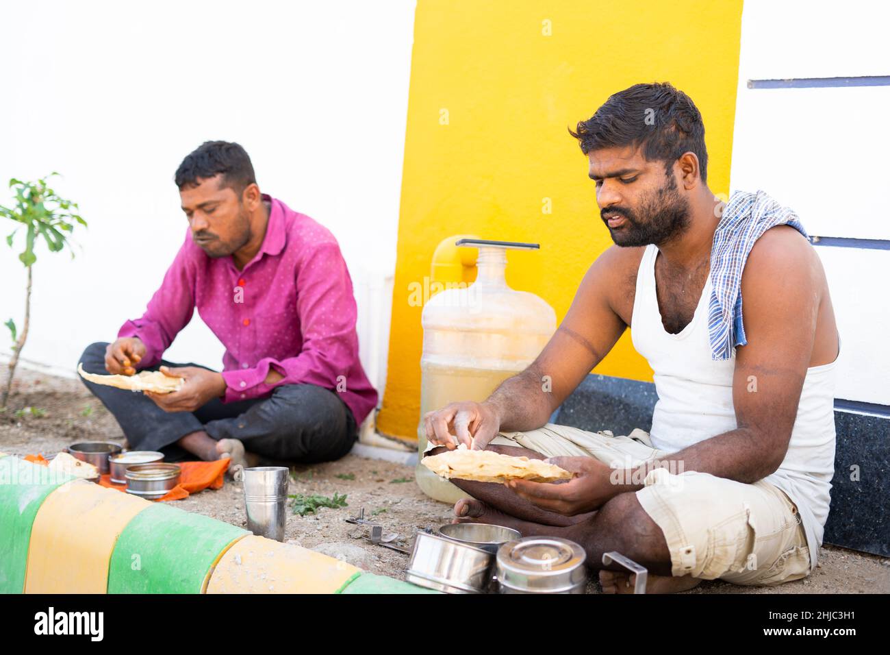 Indian construction worker busy having afternoon lunch at workplace