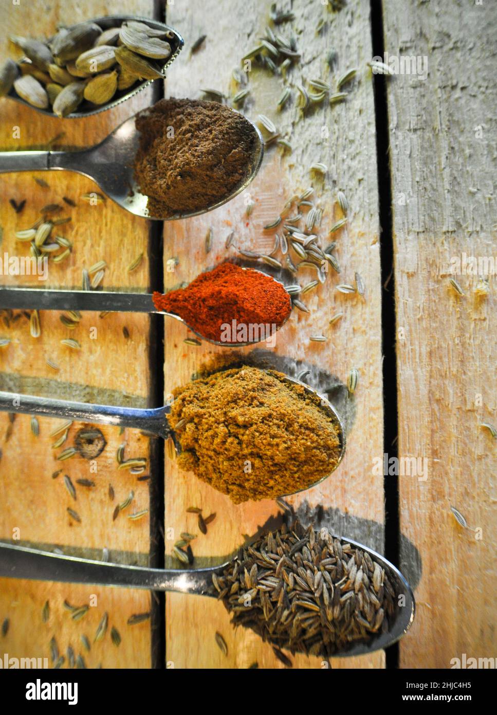 A variety of spoons with different spices on them set against a rustic wooden background. Copy space has been left Stock Photo
