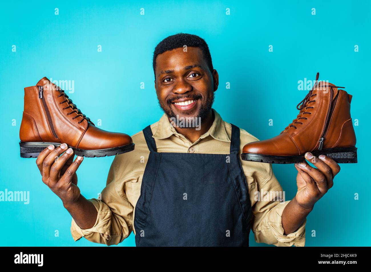 latin hispanic man in black apron showing brown leather shoes in blue