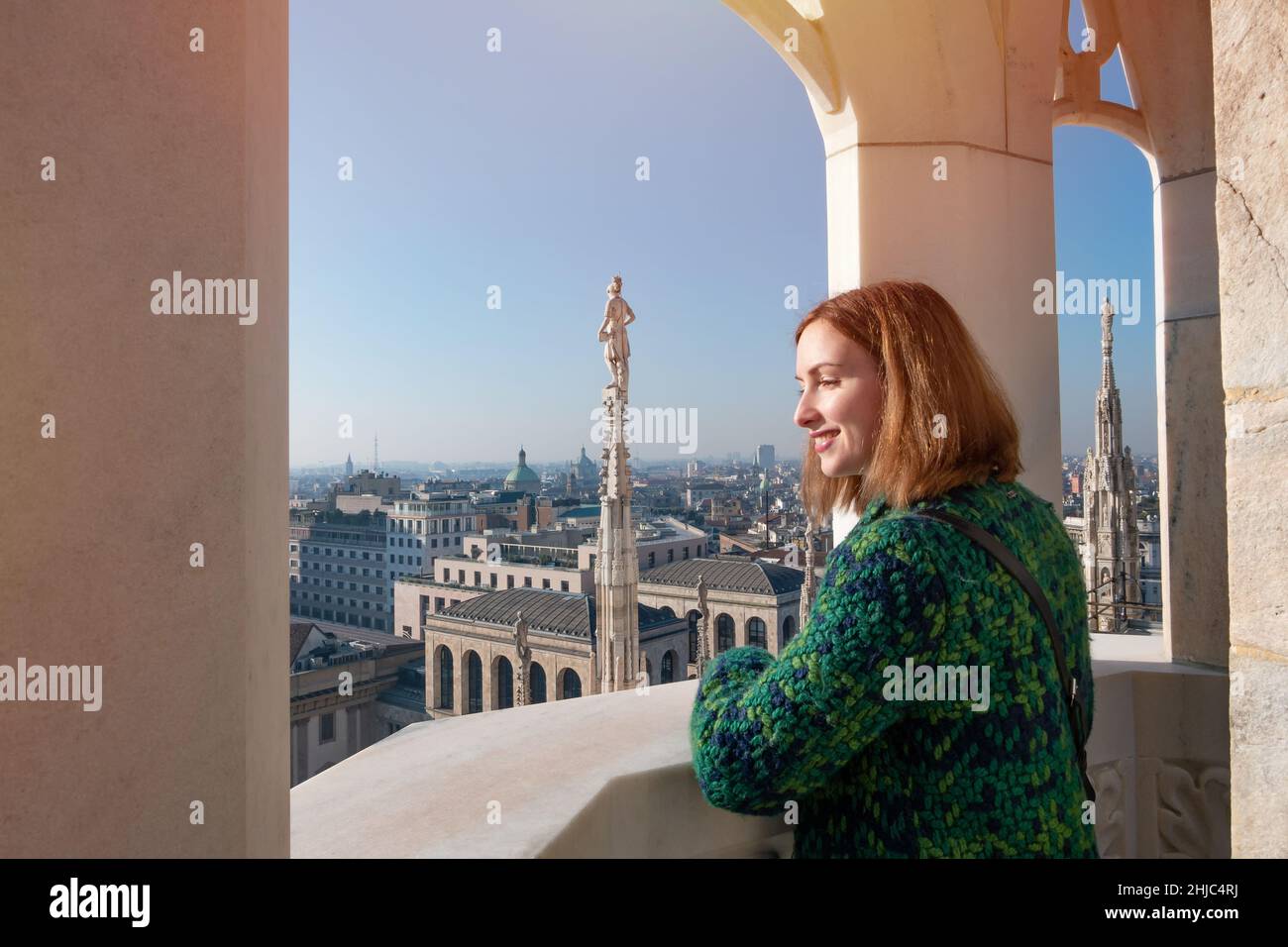 Young happy woman looking at the Milan city from the roof of Duomo Milan Cathedral window Stock Photo