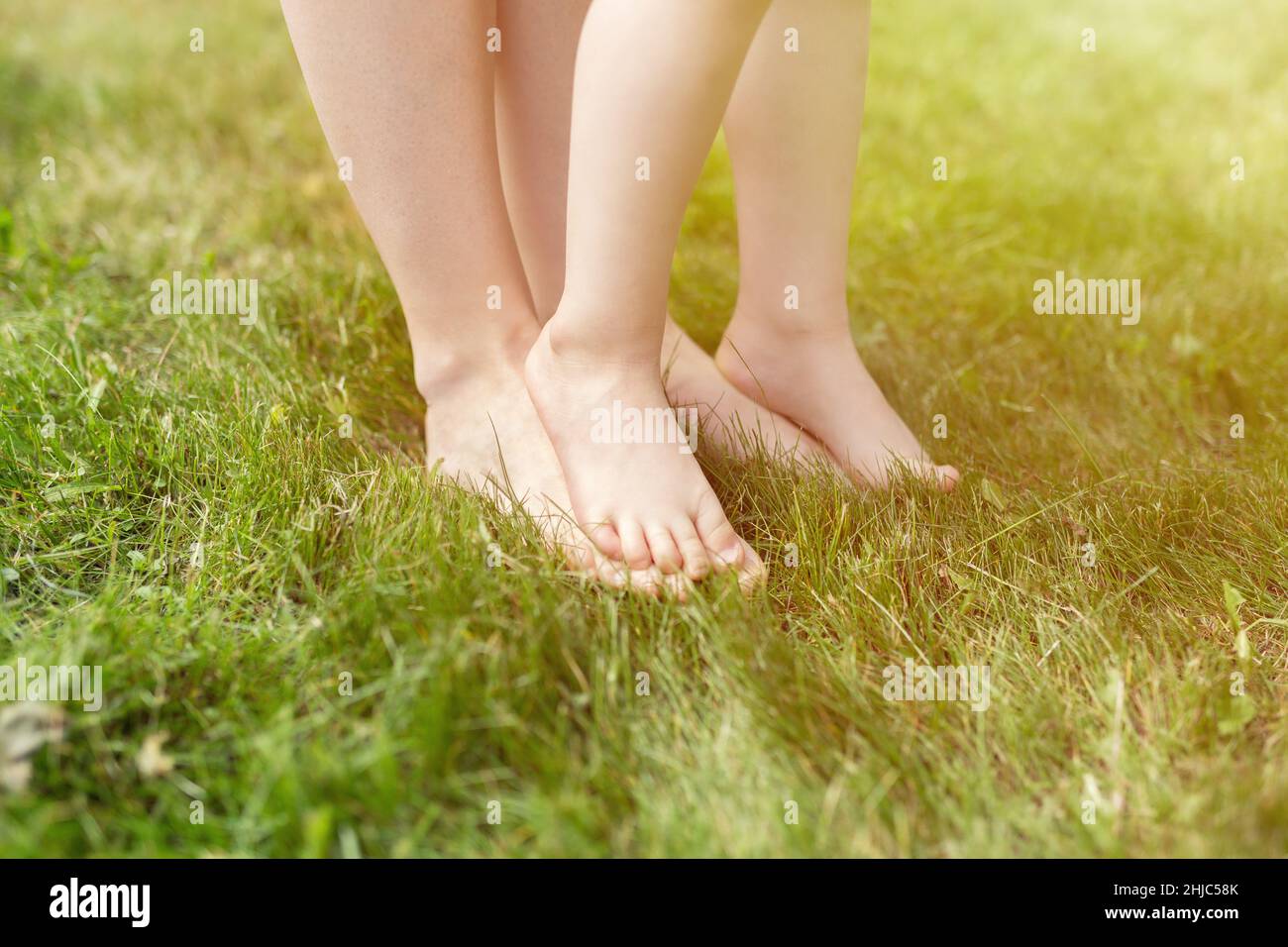 Closeup of woman and toddler kid barefeet on green grass. Mother and toddler kid walking on the grass barefeet Stock Photo