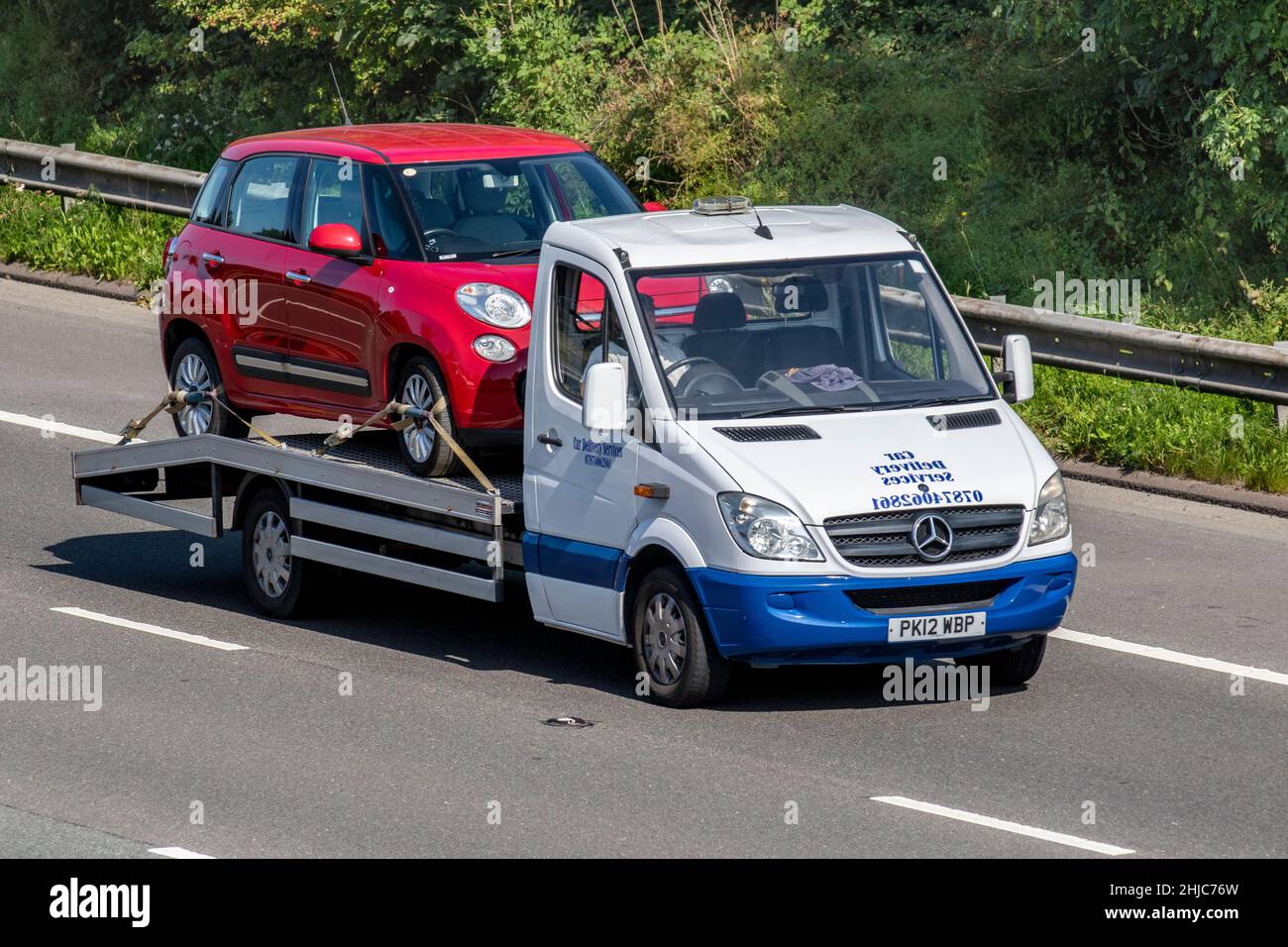 2012 white Mercedes Benz 2143cc Sprinter low-loader car delivery services carrying red Fiat 500 cross SUV on the M61 motorway, UK Stock Photo
