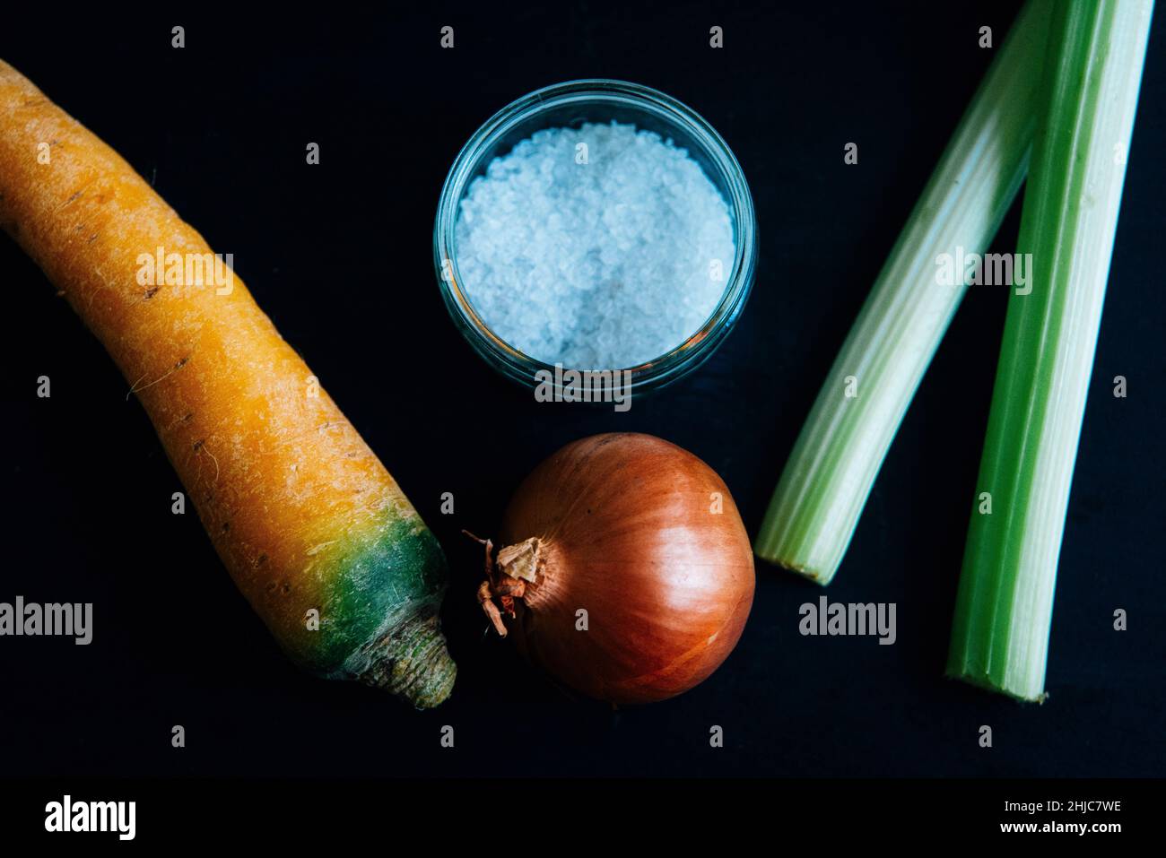 Celery, carrot and onion on slate with salt on slate. Traditional ingredients for the french culinary base mirepoix, or Italian Soffritto Stock Photo