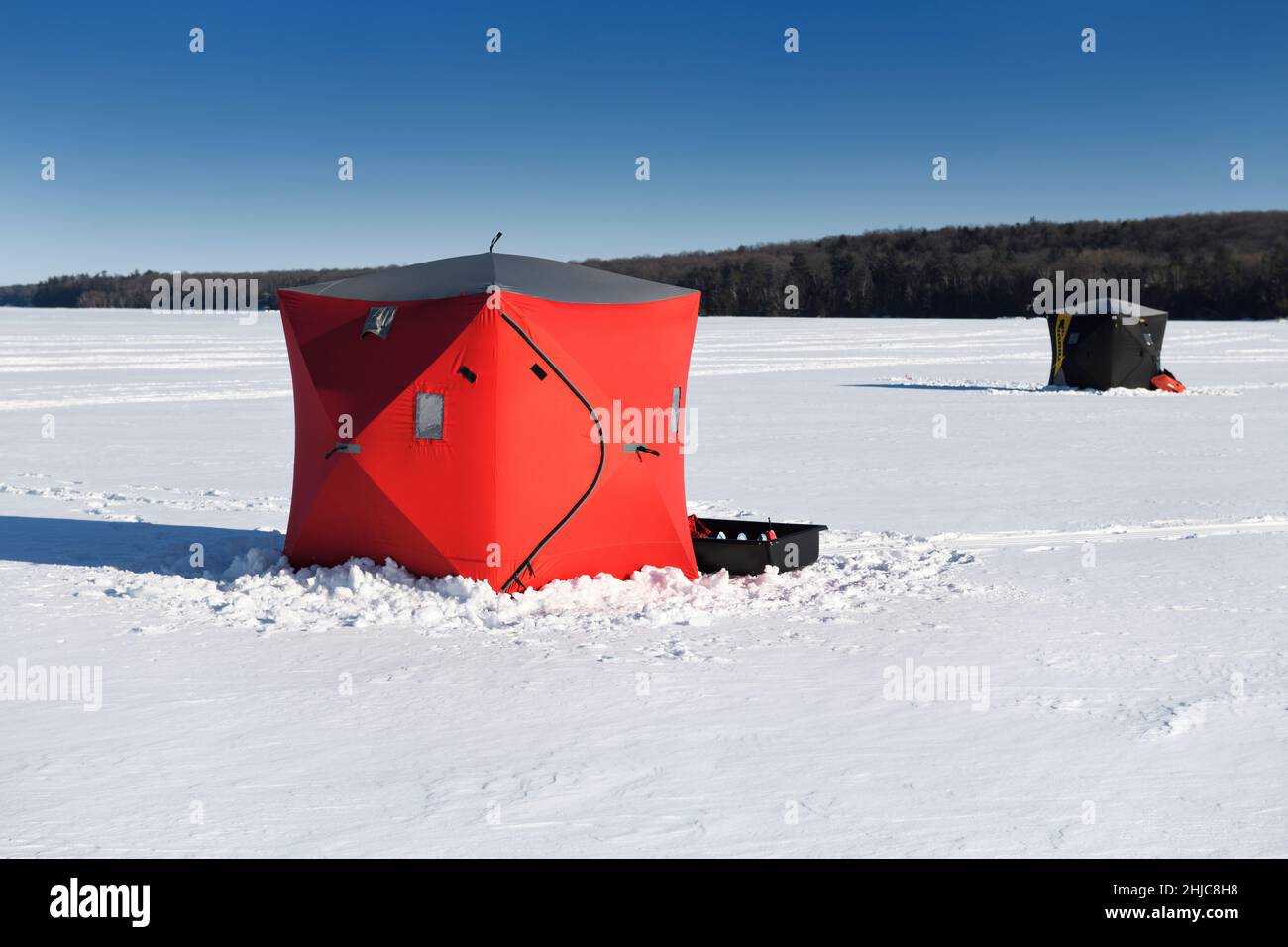 Red and black ice fishing huts in snow on frozen Kempenfelt Bay of Lake