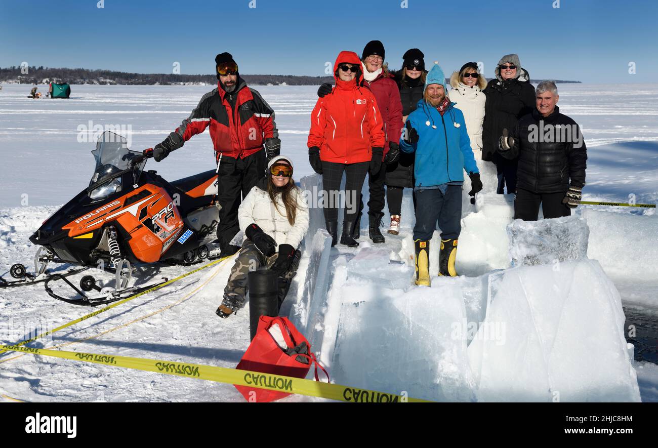 Group of smiling people in sun at an ice hole for cold water swimming in winter  at Kempenfelt Bay Lake Simcoe Barrie Ontario Stock Photo