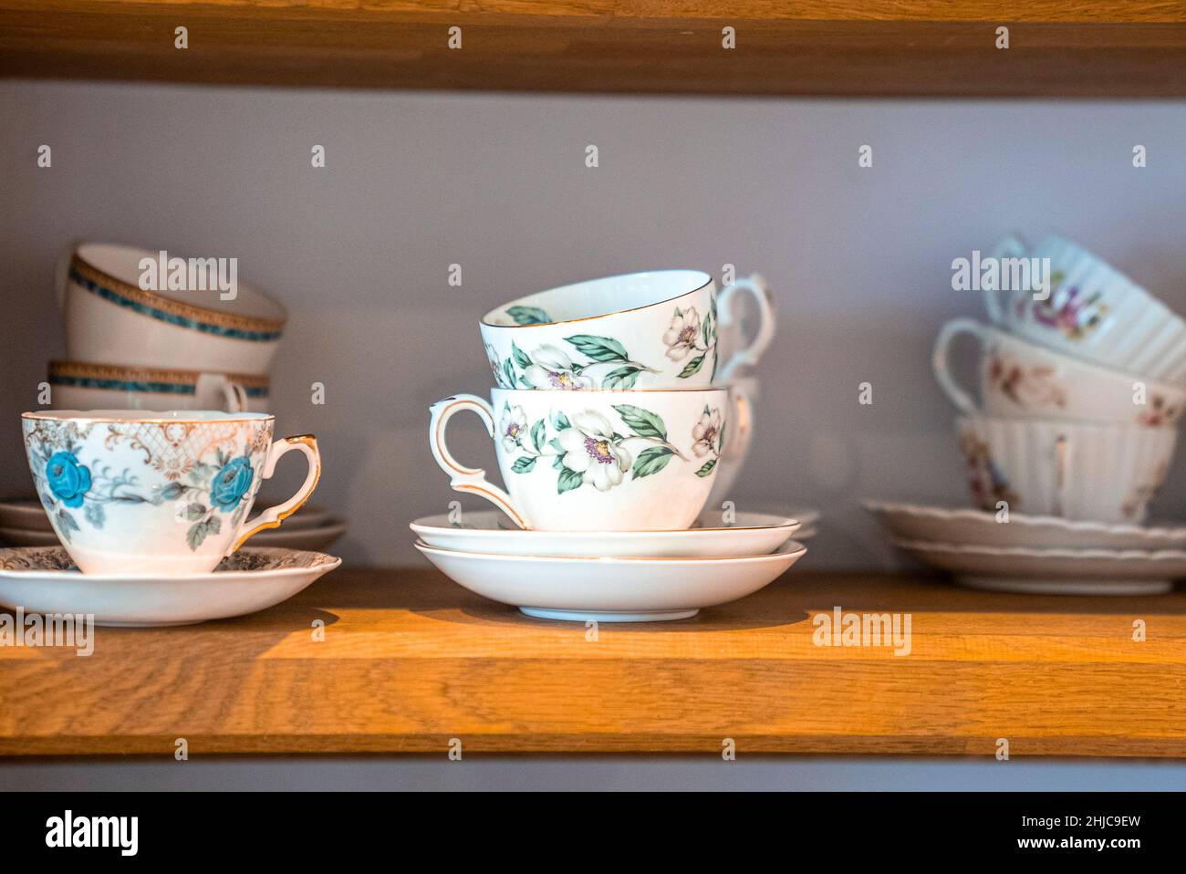 Hand painted ceramic floral pattern teacups with saucers on shelves Stock Photo