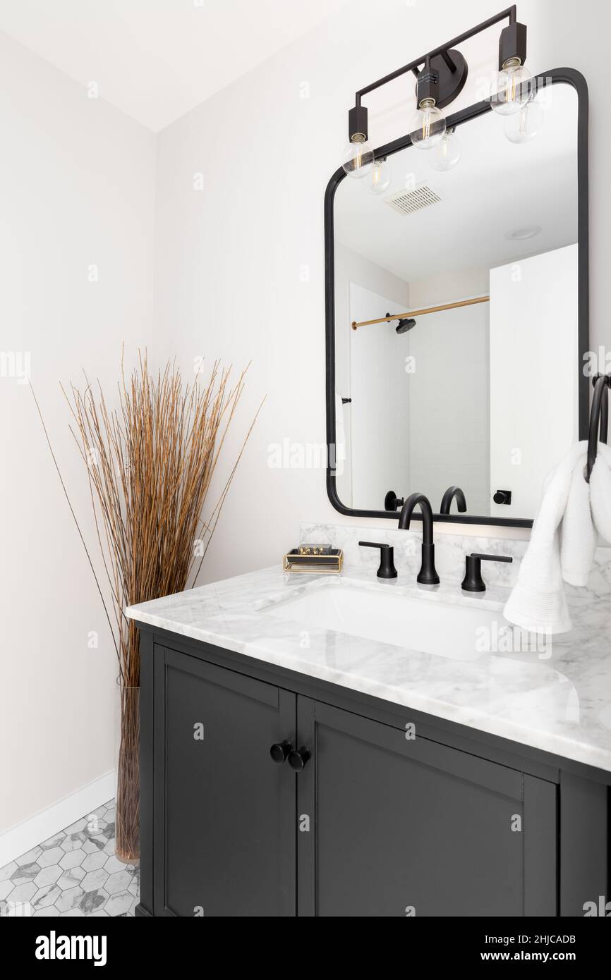 A cozy bathroom with a grey vanity hexagon marble tiled floor, and white granite
