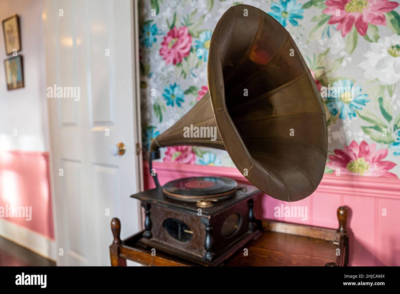 Antique brass gramophone with horn speaker on table against decor wall