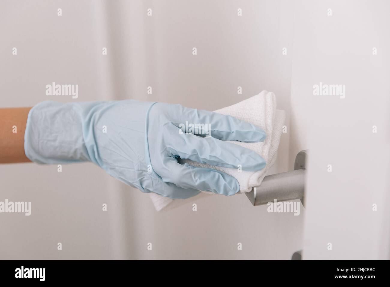 Cleaning black door handles with an antiseptic wet wipe in blue gloves