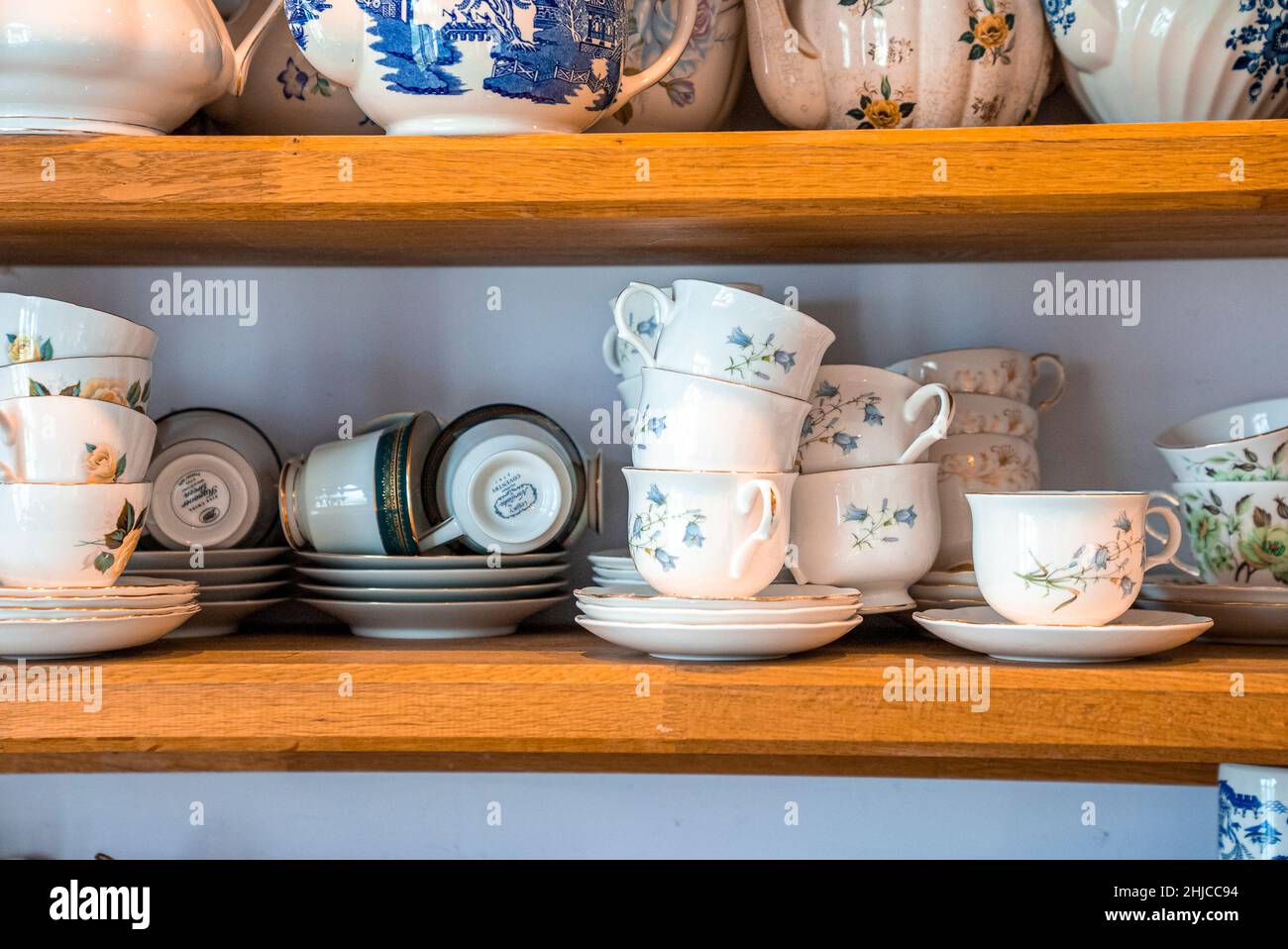 Hand painted ceramic floral pattern teacups with saucers on shelves