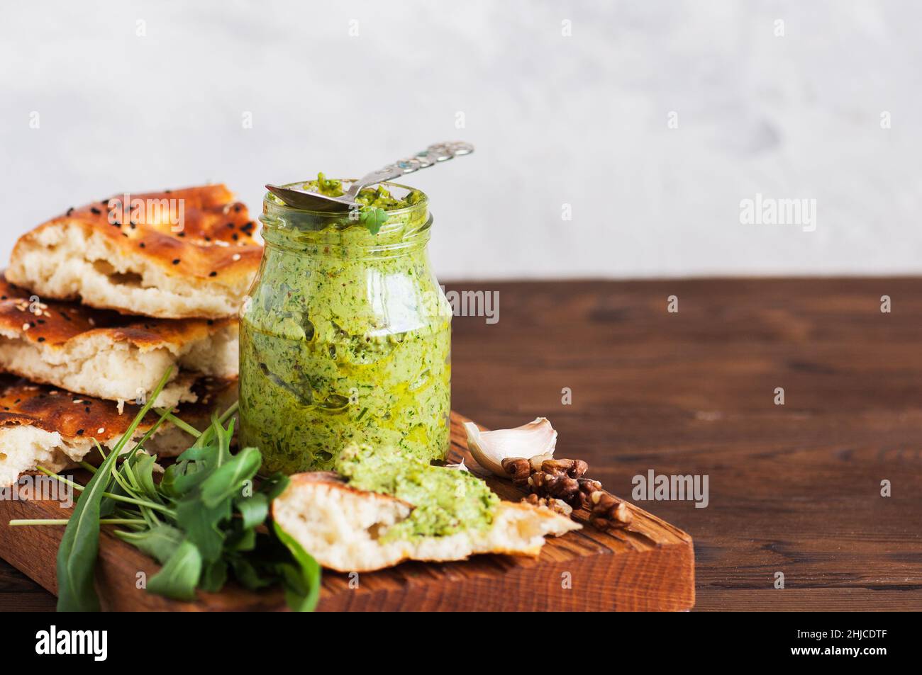 Green pesto sauce in a jar on a wooden board. Stock Photo