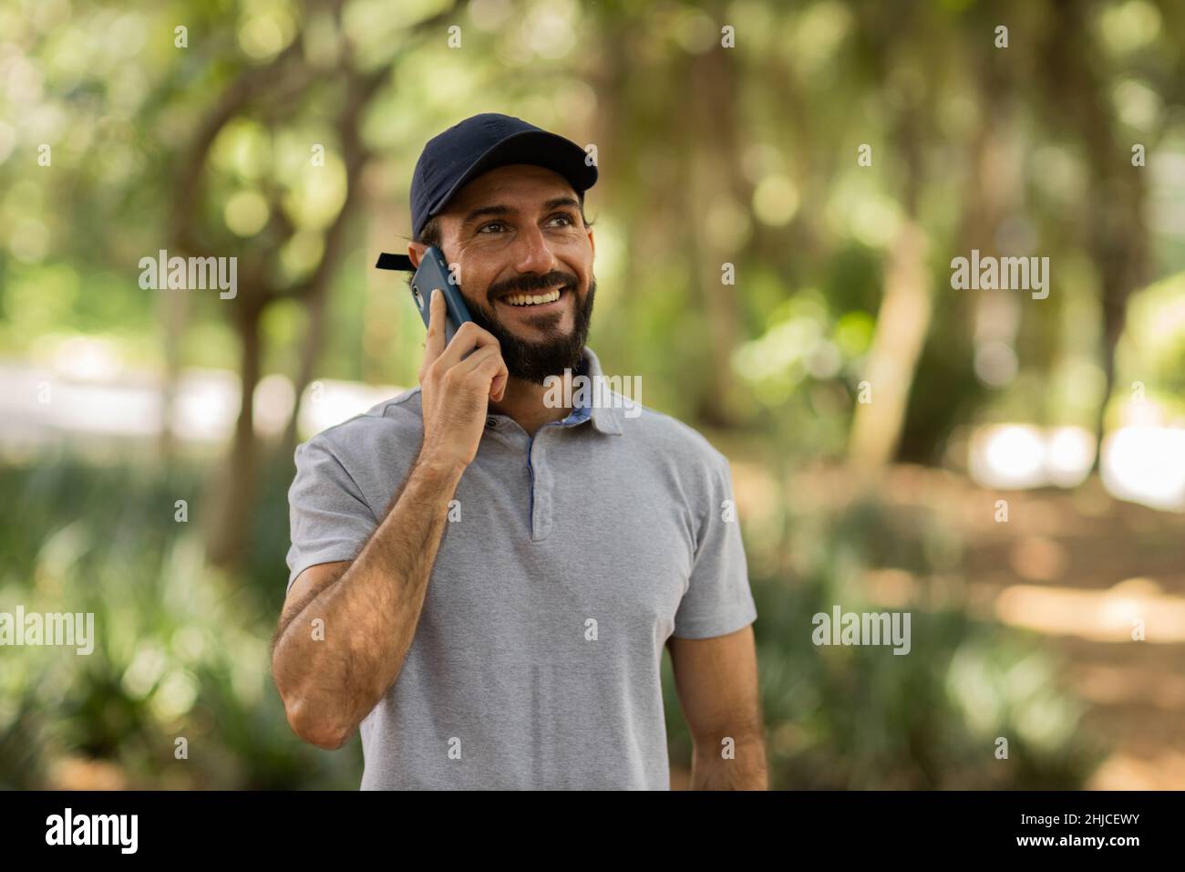 View of young man using a smartphone at day time with a green park in ...