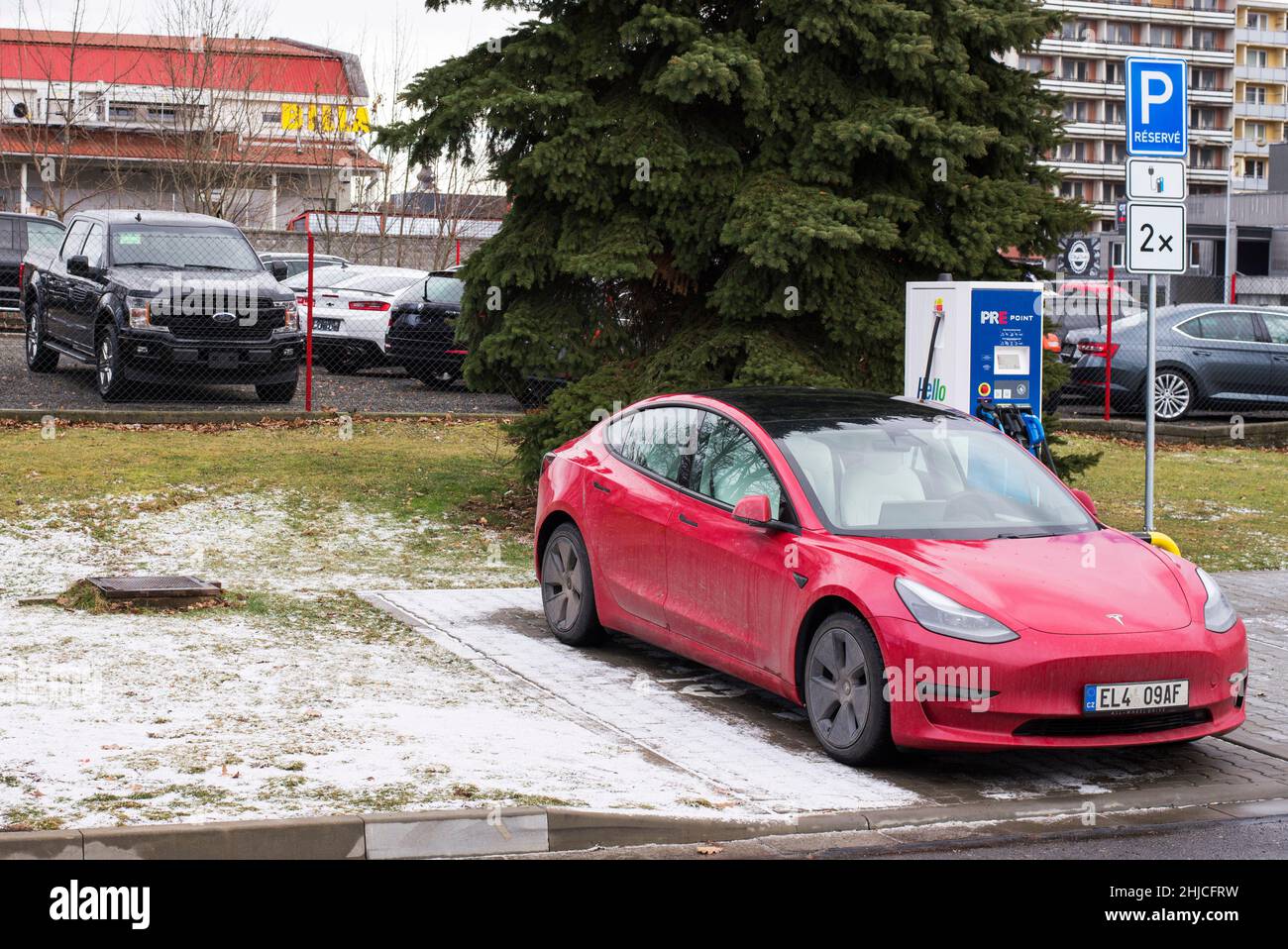Roznov Czech Republic November 20th 2022 - Tesla model S car being charged with a yellow mussle car in background Stock Photo