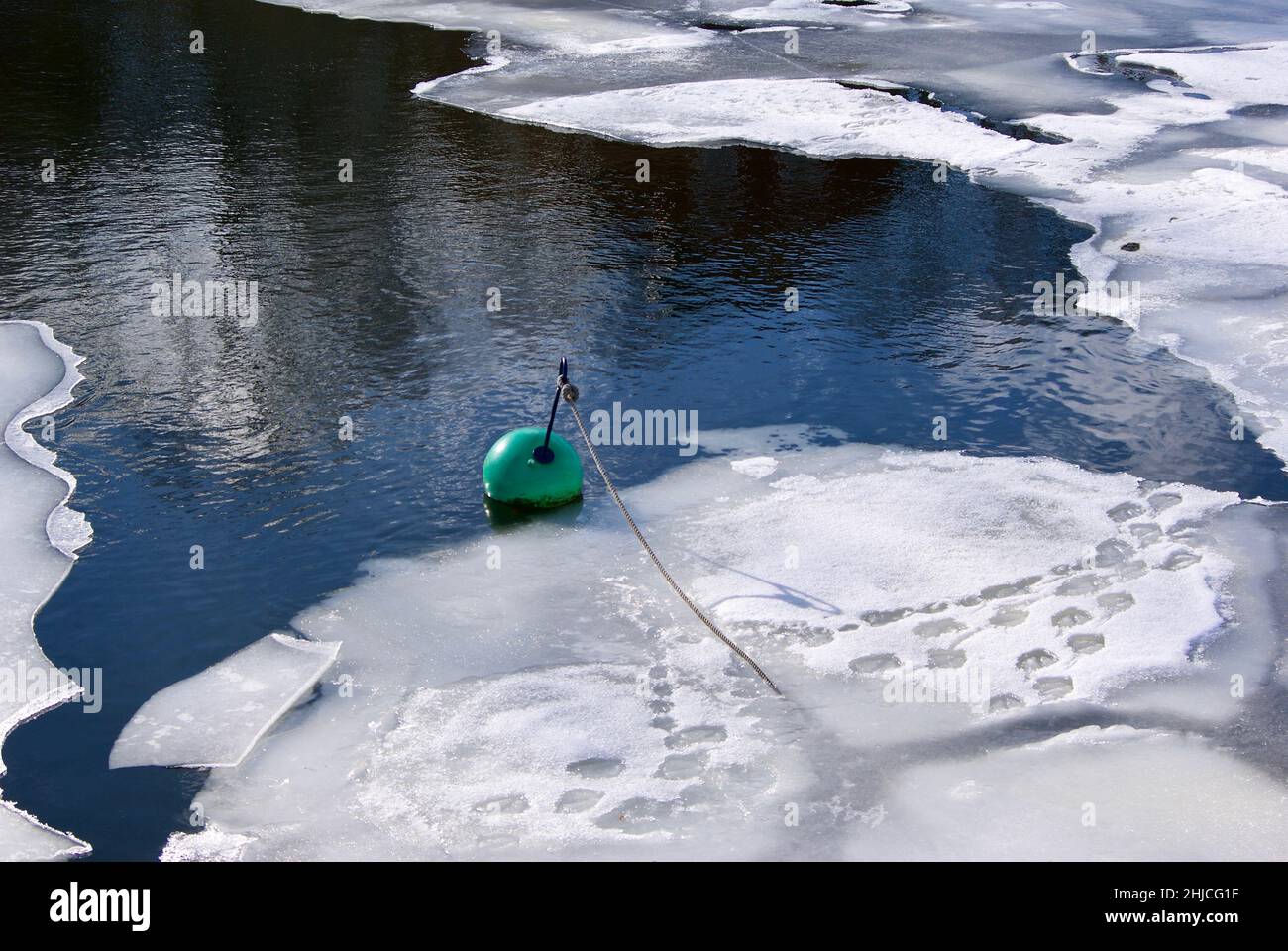 Hole in the ice with ice floes and a green buoy. Stock Photo