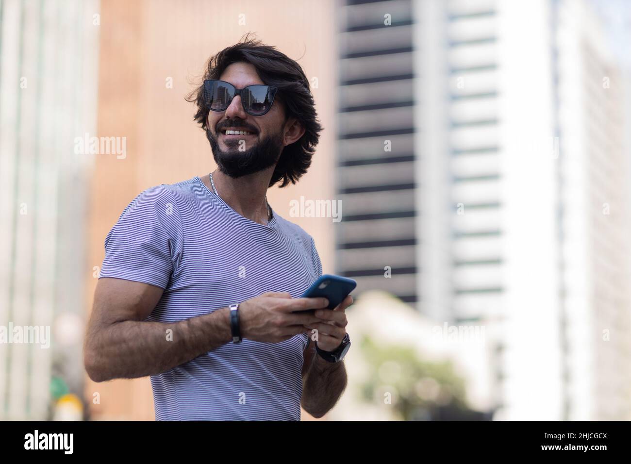 View of young man using a smartphone at day time with city view ...