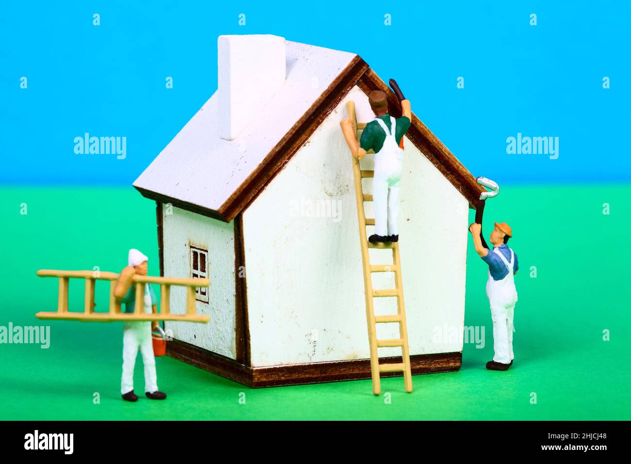 Conceptual image of miniature figure decorators painting the walls of a model house Stock Photo